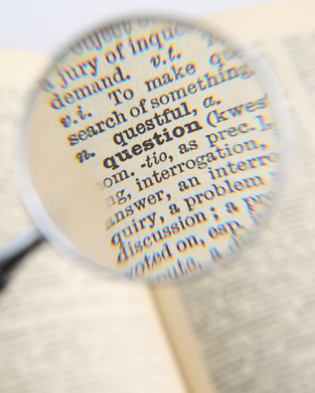 A magnifying glass pointing on the section of a dictionary that explains the word question.